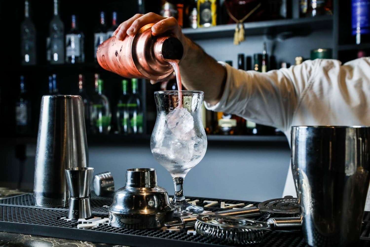 man-pouring-cocktail-from-shaker-in-the-glass-with-ice-bar-side-view (1)